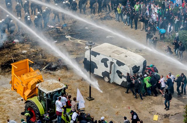 제품 가격 폭락에 항의하는 유럽 축산낙농업자들이 9월 7일 EU 농업장관 회의가 열린 벨기에 브뤼셀 EU 본부 앞에서 건초를 불 태우고 물대포를 쏘며 시위를 벌이고 있다. 브뤼셀=AP 연합뉴스