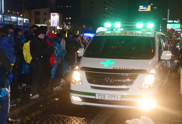 14일 저녁 서울 광화문에서 열린 민중총궐기대회에서 한 농민이 차벽에 밧줄을 걸고 당기던 중 경찰의 물대포를 직사로 맞고 쓰러져 뇌진탕 증세를 보였고, 아스팔트에 누워있다가 구급차로 호송되고 있다. 뉴시스