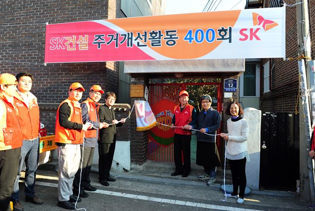 소외된 이웃들의 주거환경을 개선해주는 봉사활동이 이달 400회를 돌파했다. 조기행(오른쪽 세번째) SK건설 사장 및 임직원들이 이를 기념하며 명판식을 진행하고 있다. SK건설 제공