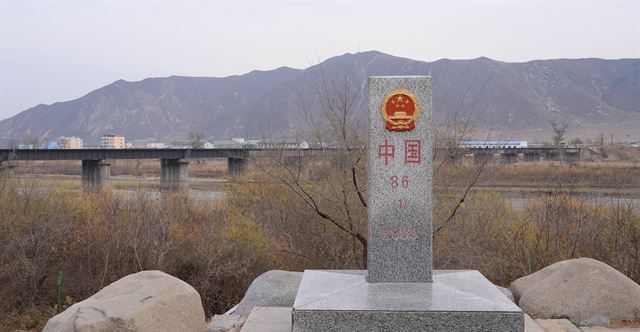 두만강을 가로질러 중국 지린성 투먼시와 북한의 남양을 연결하는 투먼 철교(사진 뒷편) 인근 강변에 중국 땅임을 알리는 비석이 세워져 있다.