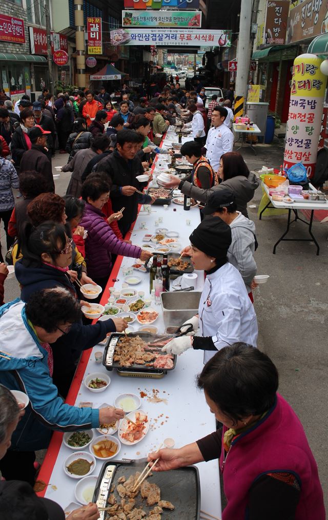 24일 오후 충북 영동군 영동전통시장내 와인삼겹살 거리에서 주민 관광객들이 와인삼겹살을 맛보고 있다. 와인에 숙성시킨 삼겹살은 육질이 부드럽고 고기 냄새가 안나는게 특징이다. 영동군 제공.