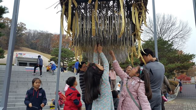 29일 젓가락특별전을 찾은 관람객들이 전시관 앞에 설치된 젓가락조형물이 바람에 흔들리며 소리를 내자 신기한 듯 만져보고 있다. 배 모양의 이 조형물은 고려가요 '동동'에 젓가락 재료로 나오는 분디나무가 골격을 이루고 아랫부분에 가느다란 쇠젓가락 수백개가 매달려있다. 바람이 불면 배가 조금씩 흔들리며 쇠젓가락들이 청량한 소리를 낸다. 동아시아문화도시청주 조직위 제공.