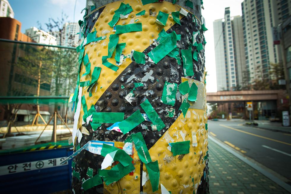 서울 동작구 노량진에서 한 행인이 불법 광고물과 테이프 잔해로 뒤덮인 벽 앞을 지나고 있다.