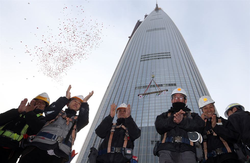 22일 서울 송파구 롯데월드타워의 꼭대기층 123층에 대들보를 얹는 상량식이 열렸다. 주요인사들의 서명이 적힌 H빔 대들보가 타워크레인 줄에 매달려 올려지고 있다. 홍인기기자 hongik@hankookilbo.com