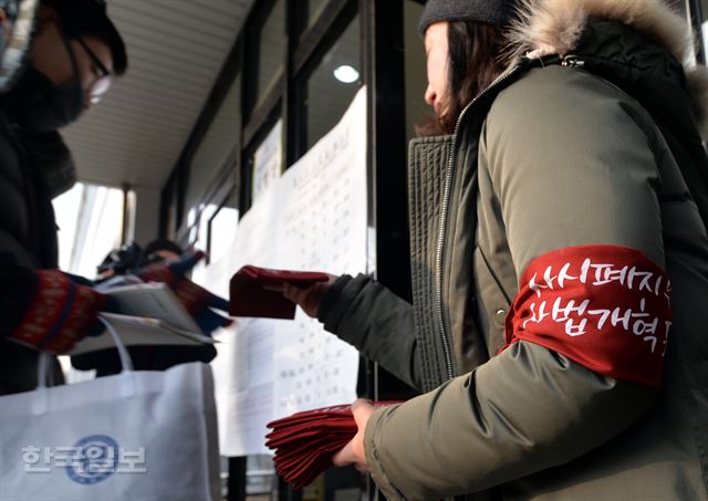 4일 오전 서울 서대문구 연세대 백양관에서 제5회 변호사시험이 실시되는 가운데 법학전문대학원 학생협의회원들이 '사시폐지 유예는 사법개혁 포기다'라는 문구가 적힌 손수건을 응시자들에게 나눠주고 있다. 서재훈기자 spring@hankookilbo.com