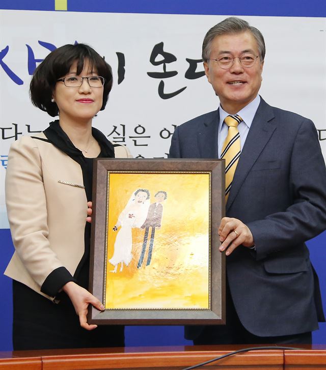 문재인 더불어민주당 대표가 6일 국회 당 대표실에서 열린 김선현 차의과대학교 교수 입당 기자회견에서 김 교수로부터 그림 ‘결혼’을 전달받고 있다. 연합뉴스