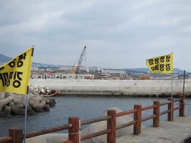 강정포구 방파제에서 바라본 해군기지 건설현장. 기지와 그 부속건물까지 완공을 앞둔 상황이지만 마을 곳곳엔 여전히 기지를 반대하는 깃발과 현수막이 나부끼고 있다. 황수현기자 sooh@hankookilbo.com