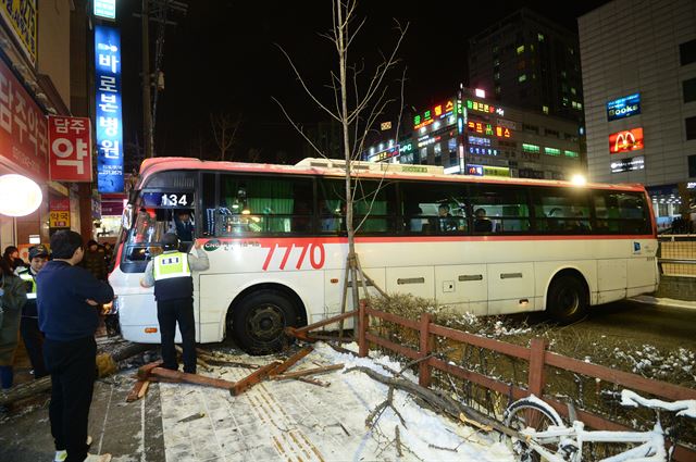 경기 남부 일부 지역에 내린 눈이 얼어붙으면서 13일 오후 경기 수원시 장안지하차도 인근에서 광역버스가 빙판길에 미끄러져 승용차와 가로수를 잇따라 들이 받는 사고가 발생해 경찰과 소방대원들이 사고수습작업을 하고 있다. 연합뉴스