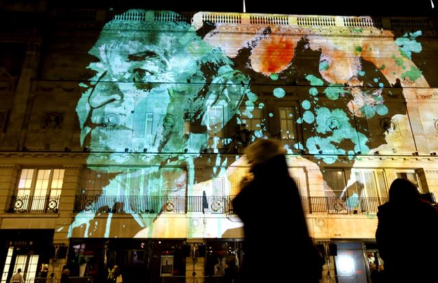 영국 런던에서 14일(현지시간) '루미에르 빛 축제(Lumiere festival)'가 열린 가운데 시민들이 물든 예술가 노박의 '195 피카딜리'가 투사되고 있는 건물 앞을 지나가고 있다. 런던=AP 연합뉴스