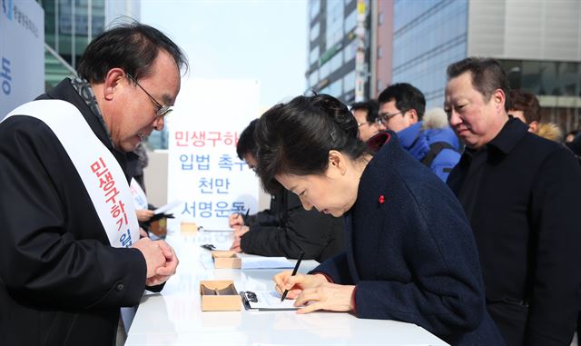 박근혜 대통령이 18일 경기 판교역 앞 광장에서 대한상공회의소 등 재계가 주도하는 경제활성화 관련 입법촉구 1,000만 서명운동 행사 부스를 찾아 직접 서명을 하고 있다. 청와대사진기자단