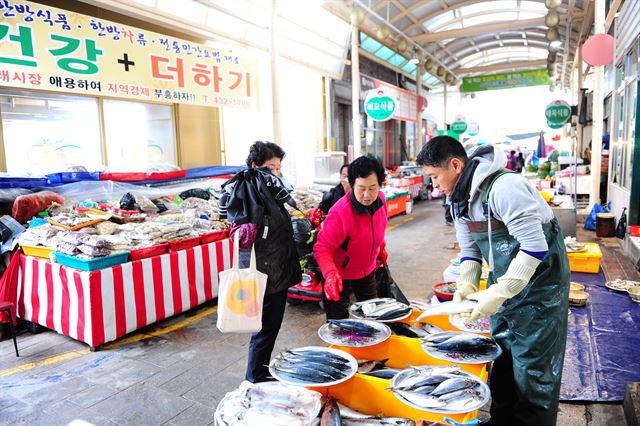 21일 김천시에 있는 전통시장의 한 상인이 추운 날씨 속에 좌판에 진열된 생선을 팔고 있다.