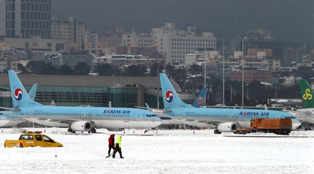 사상 초유의 제주공항 항공기 중단 사태가 3일째 이어진 25일 한국공항공사 제주지역본부의 제설차량이 계류장에서 항공기 운항 재개를 위해 제설작업을 벌이고 있다. 제주=연합뉴스