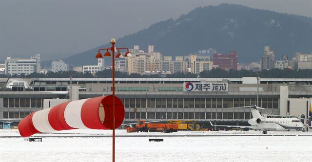 사상 초유의 제주공항 항공기 중단 사태가 3일째 이어진 25일 한국공항공사 제주지역본부의 제설차량이 계류장에서 제설작업을 벌이고 있다. 제주=연합뉴스