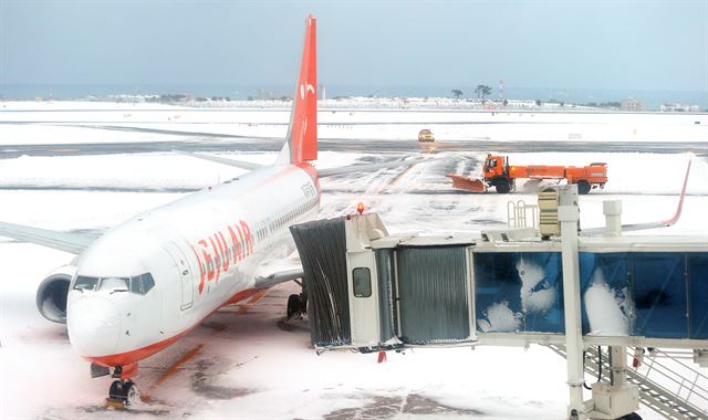 사상 초유의 제주공항 항공기 중단 사태가 3일째 이어진 25일 한국공항공사 제주지역본부의 제설차량이 계류장에서 제설작업을 벌이고 있다. 제주=연합뉴스