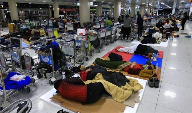 사상 초유의 제주공항 항공기 중단 사태가 3일째 이어진 25일 새벽 고단 하루를 마친 체류객들이 제주공항 여객터미널에서 잠을 자고 있다. 제주=연합뉴스