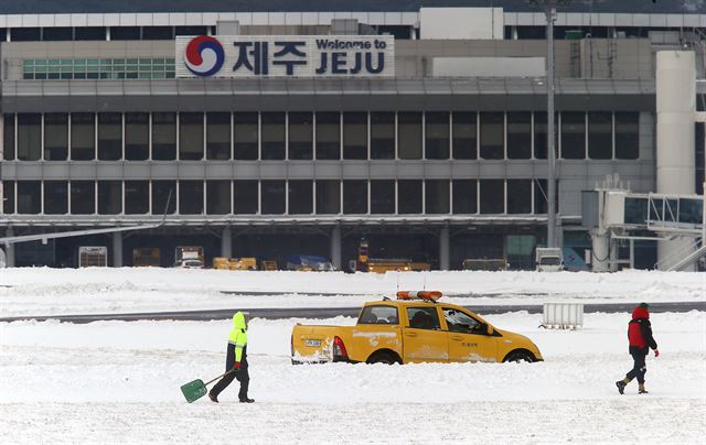 사상 초유의 제주공항 항공기 중단 사태가 3일째 이어진 25일 한국공항공사 제주지역본부의 제설차량이 계류장에서 제설작업을 벌이고 있다. 제주=연합뉴스