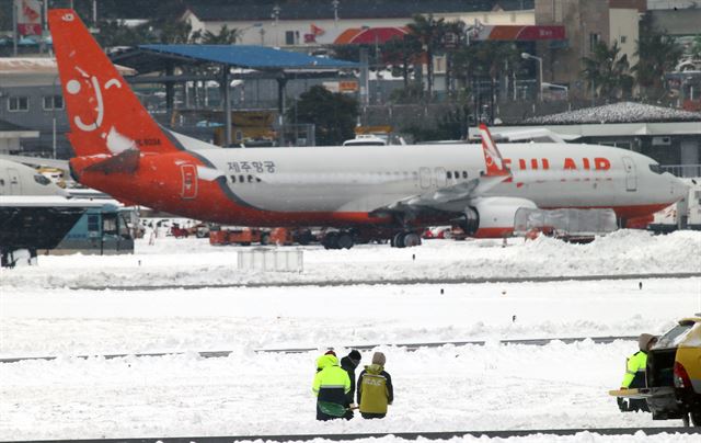 사상 초유의 제주공항 항공기 중단 사태가 3일째 이어진 25일 한국공항공사 제주지역본부의 제설차량이 계류장에서 제설작업을 벌이고 있다. 제주=연합뉴스