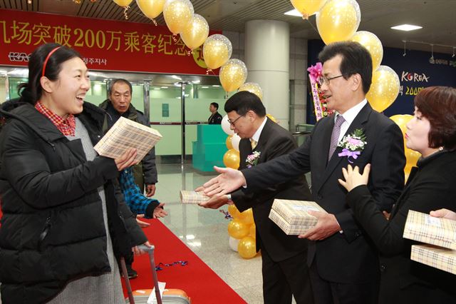 지난해 청주공항 이용객 200만명 돌파를 기념해 이시종(오른쪽)충북지사가 청주공항으로 입국하는 중국 관광객에게 기념품을 전달하고 있다. 청주공항은 중국인 무비자환승공항으로 지정된 뒤 중국 관광객이 급증하고 있지만 이들이 지역경제에 미치는 영향은 아주 미미하다는 지적이 많다. 충북도 제공