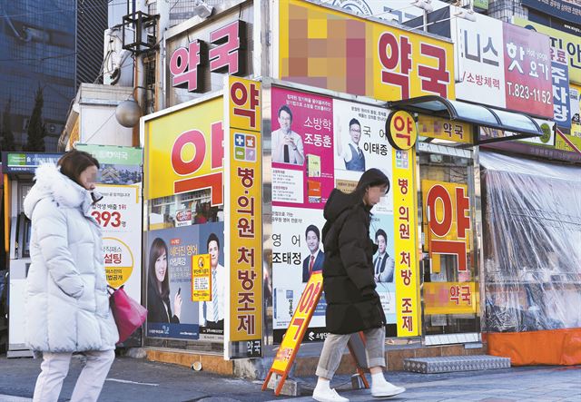 유동 인구가 많은 한 약국 외벽이 학원강사와 교재 이미지로 덮여 있다.