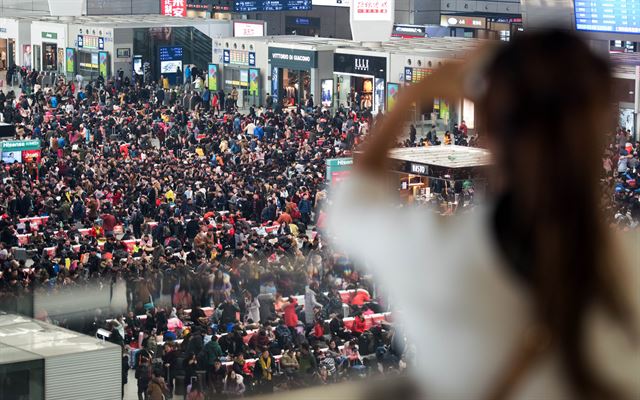 7일부터 시작되는 춘절연휴를 앞두고 3일 중국 상하이 홍차오 기차역에서 한 여성이 기차 탑승을 기다리고 있는 귀성인파를 바라보고 있다. 춘제특별운송기간인 40일 동안 연 인원 29억 1000만 명이 이동할 것으로 예상되고 있다. 상하이=AFP 연합뉴스