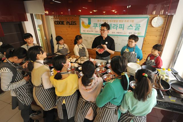 3일 오후 서울 성동구 금호동의 한 요리교실에서 열린 '쿠킹테라피'에 참석한 아이들이 요리에 앞서 강사의 설명을 듣고 있다. 중구청 제공