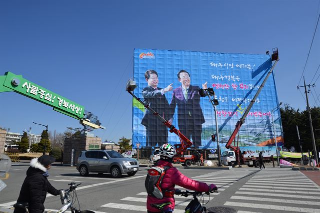 대구 시민들이 17일 경북도청 입구에 내걸리는 경북 대구 상생화합 대형 현수막을 바라보고 있다. 경북도는 20일까지 이전을 끝내고 22일 안동 예천 신도시에서 신청사 시대를 연다. 전준호기자 jhjun@hankookilbo.com/2016-02-17(한국일보)