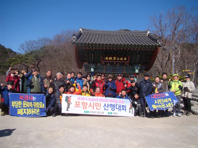 포항시민 100여 명이 21일 경북 포항시 북구 송라면 보경사 입구에서 문화재 관람표 폐지를 촉구하는 구호를 외치고 있다. 포항경제정의실천시민연합과 SNS 모임 ‘페이스북 포항’은 이날 포항시민 산행대회를 통해 보경사가 올해 11억2,500만원의 혈세를 지원받고도 입장객 개인 당 최고 3,500원의 문화재 관람료를 받는 것이 부당하다고 지적했다. 김정혜기자 kjh@hankookilbo.com