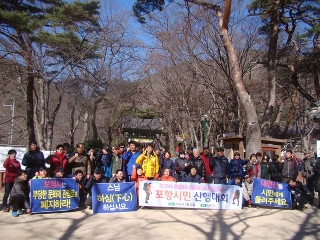 포항시민 100여 명이 21일 경북 포항시 북구 송라면 보경사 입구에서 문화재 관람표 폐지를 촉구하는 구호를 외치고 있다. 포항경제정의실천시민연합과 SNS 모임 ‘페이스북 포항’은 이날 포항시민 산행대회를 통해 보경사가 올해 11억2,500만원의 혈세를 지원받고도 입장객 개인 당 최고 3,500원의 문화재 관람료를 받는 것이 부당하다고 지적했다. 김정혜기자 kjh@hankookilbo.com