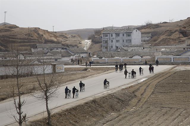 북한 로켓 발사에 대한 제제 조치로 개성공단이 가동 전면 중단된 지 12일이 지난 22일(현지시간) 북한 개성에서 북한 주민들이 자전거를 밀며 걸어가고 있다. 개성=AP 연합뉴스