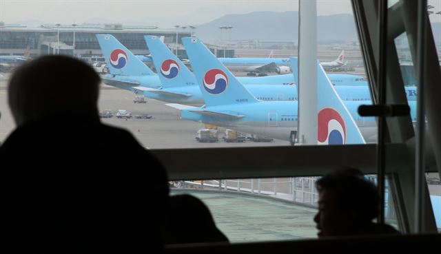 19일 오후 인천공항 출국장에서 여행객들이 대한항공 여객기들을 바라보고 있다. 연합뉴스