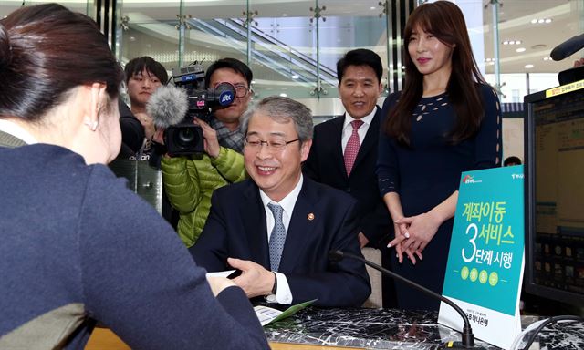 2월25일 서울 명동 KEB하나은행 본점 영업부에서 열린 계좌이동서비스 3단계 시연행사에서 임종룡 금융위원장이 서비스 신청을 마친뒤 통장을 받고있다. 홍인기기자 hongik@hankookilbo.com