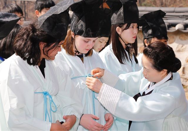 외국인 유학생들이 16일 열린 회덕향교 춘기 석전대제에서 향교 관계자의 도움을 받아 의관을 바로잡고 있다. 대전 대덕구 제공/2016-03-16(한국일보)