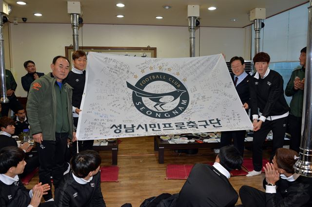 성남FC 선수단이 지난 16일 회식 뒤 구단 깃발을 펼쳐보이며 승리를 다짐하고 있다. 이 구단기는 성남의 아줌마 팬들로 구성된 '줌마 서포터스'가 제작한 것으로 수원FC와 경기에서 이기면 이 깃발이 수원종합운동장에 걸리게 된다. 성남FC 제공