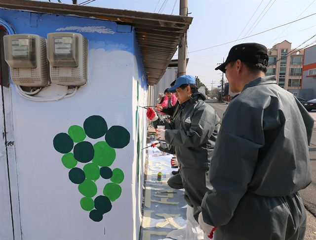 김학동 포스코 포항제철소장과 포스코패밀리 임직원들이 지난 26일 경북 포항 남구 청림동 주택가를 방문해 담장에 벽화를 그리고 있다. 포스코 제공.