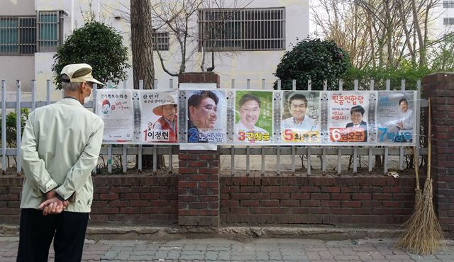 전남 순천시 연향동의 한 아파트 담장을 지나가던 할아버지가 20대 총선 순천지역 후보자 선거벽보를 훑어보고 있다. 순천=하태민기자 /2016-04-03(한국일보)