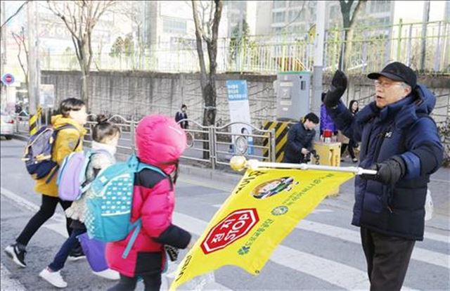 정든 교단을 떠난 뒤에도 충남 공주 신월초교 교통안전 지킴이 역할을 맡고 있는 조동수 전 교장이 길을 건너는 아이들에게 손을 흔들고 있다. 연합뉴스