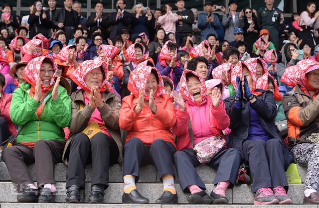 [저작권 한국일보] 8일 오후 서울 용산 전쟁기념관을 찾은 시민들이 봄 햇살을 피하기 위해 머리에 수건을 쓴 채 육·해·공 3군 통합의장대원들이 의장시범을 보며 환호하고 있다. 배우한기자 bwh3140@hankookilbo.com