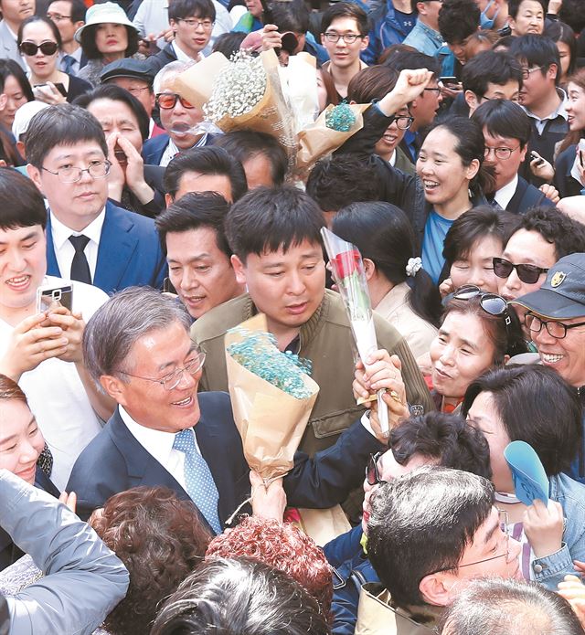 문재인 더불어민주당 전 대표가 8일 오후 광주 충장로 우체국 앞에서 '광주시민들에게 드리는 글' 발표를 마친 뒤 충장로를 빠져나가며 지지자들로부터 꽃다발을 받고 있다. 연합뉴스