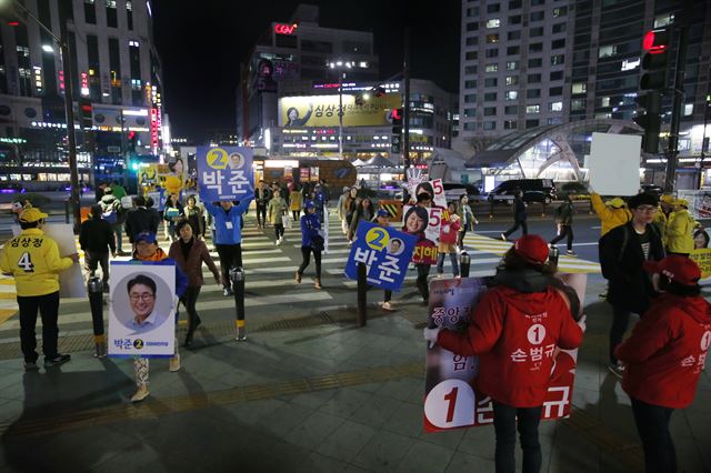 선거유세 기간 종료를 앞둔 12일 밤 경기도 고양시 화정역에서 경기 고양갑에 출마한 정의당 심상정 후보 운동원(노란색 옷)들과 새누리당 손범규 후보 운동원들(붉은색 옷), 더불어민주당 박준 후보 운동원들(파란색 옷)이 마지막 유세를 벌이고 있다. 연합뉴스