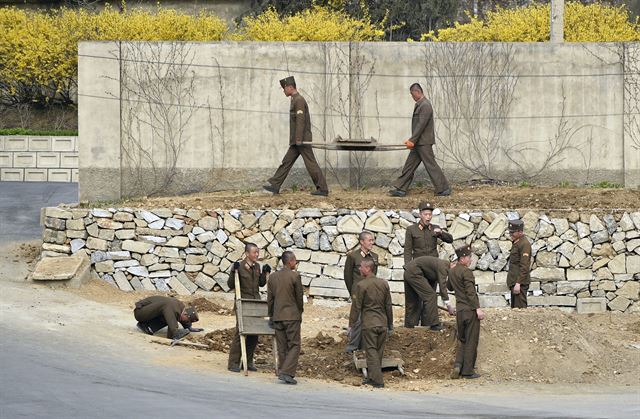 지난 12일 촬영해 14일 공개한 것으로 개나리가 활짝 핀 평양 근교에서 작업 중인 북한 군인들. EPA 연합뉴스