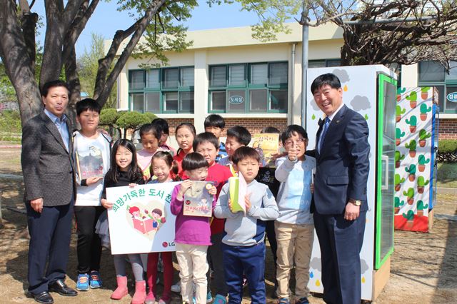 청주 옥산초등학교 소로분교 어린이들이 18일 LG화학으로부터 책을 선물받은 뒤 양충직 교장(오른쪽)과 함께 기뻐하고 있다. LG화학 제공.