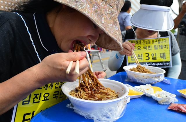 대한민국어버이연합과 보수단체 회원들이 2014년 8월27일 서울 광화문에서 열린 세월호 선동세력 규탄집회에서 세월호 단식을 조롱하며 자장면을 먹는 퍼포먼스를 하고 있다. 한국일보 자료사진