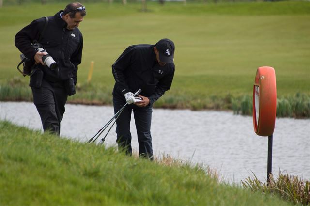 Chief White House Photographer Pete Souza (L) helps US President Barack Obama (R) look for his ball in the rough outside the 3rd green during a round with British Prime Minister David Cameron at The Grove Golf Course in Hertfordshire, April 23, 2016. (AFP PHOTO / Jim Watson)