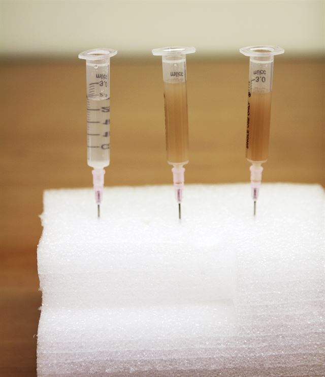 물에 모래가루를 넣어 흡입한 결과. 일체형 필터주사기(사진 가운데)와 일반주사기(사진 오른쪽)는 모래가루가 삽입돼 뿌옇게 흐려졌다. 사진 왼쪽은 분리형 필터주사기. 한국일보 자료사진
