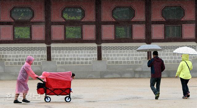 서울을 비롯한 전국에 대지를 적시는 봄비가 내린 15일 오후 서울 경복궁을 찾은 관광객이 내리는 비를 피하기 위해 유아웨건에 비닐을 씌운채로 관광을 하고 있다. 서재훈기자