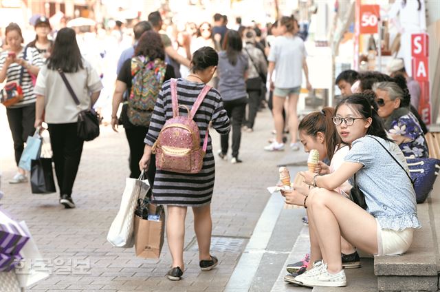 메르스 첫 환자 발생 1년을 하루 앞둔 19일 활기를 되찾은 서울 명동 거리에서 관광객들이 아이스크림을 먹고 있다. 명동을 방문하는 중국인 관광객 대부분이 식당에서 식사를 하기보다는 노점의 값싼 먹거리를 더 많이 찾는 등 주머니를 활짝 열지 않아 상인들이 속을 태우고 있다. 배우한 기자 bwh3140@hankookilbo.com