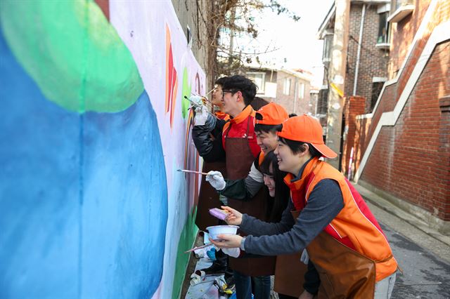 SK이노베이션 신입사원 40여명이 지난 2월 서울 상도동 밤골마을에서 벽화그리기 봉사활동을 펴고 있다. SK이노베이션 제공