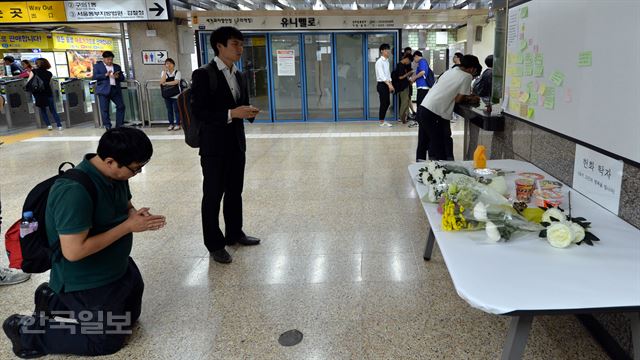 30일 오후 서울 광진구 구의역 4번출구 앞에 스크린도어 정비 작업중 사고로 숨진 김모(19) 씨를 추모하는 한 시민이 헌화 후 기도를 하고 있다. 이 국화와 포스트잇은 원래 지하철 스크린도어 앞에 놓여져 있었으나 구의역 관계자가 안전상의 이유로 옮겨 놓았다. 서재훈기자