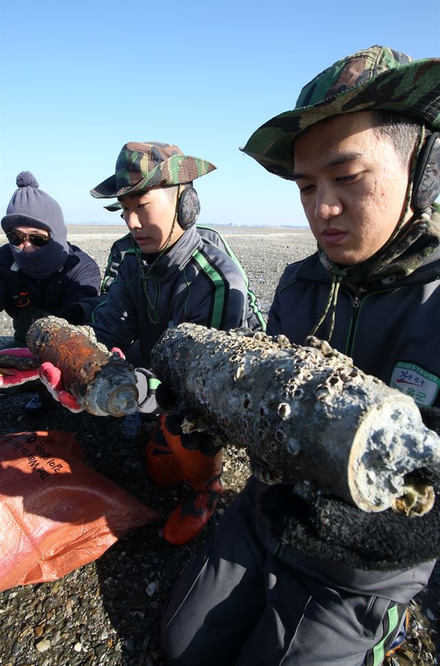 육군 51사단 장병들이 2013년 12월 매향리 농섬 주변에서 환경정화작업 중에 수거한 사격 잔재물을 들고 있다. 2012년 국방부 용역결과 사격잔재물의 99%는 농섬 반경 500ｍ 이내에 산재해 있는 것으로 확인됐다.