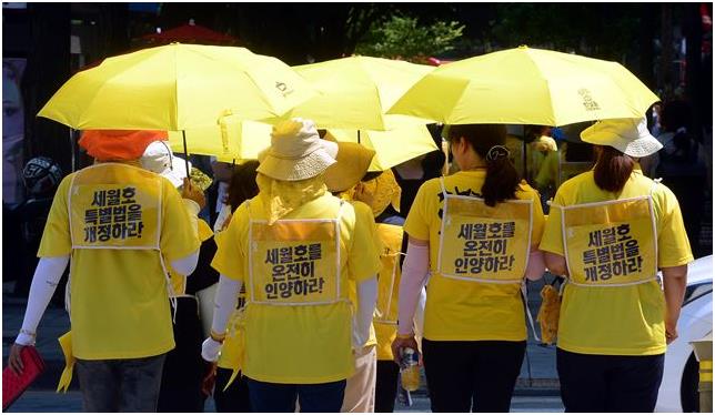 26일 서울 종로구 정부서울청사 앞에서 무기한 농성을 시작한 세월호 참사 유가족들이 ‘세월호 특별법을 개정하라’ ‘세월호를 온전히 인양하라’는 문구를 몸에 두르고 서 있다. 이날 농성 중이던 유경근 4ㆍ16연대집행위원장 등 유가족 4명은 햇볕을 막기 위해 농성장에 설치해 놓은 차양막을 경찰이 압수하는 과정에서 항의를 하다가 연행됐다. 뉴시스